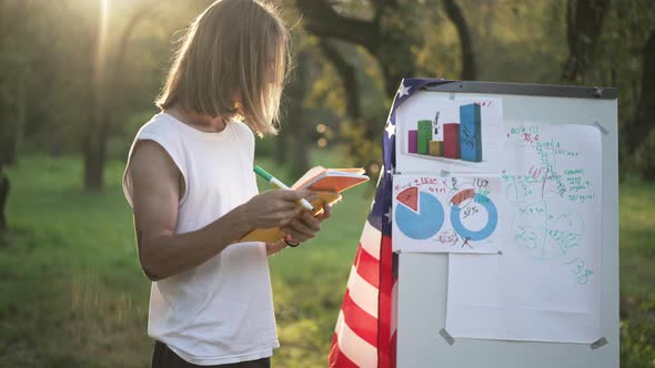 Focused Young Man Standing at Whiteboard with American Flag Writing Ideas with Pen
