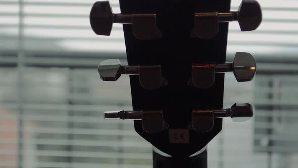 Black guitar neck with silver tuning mechanism by the window