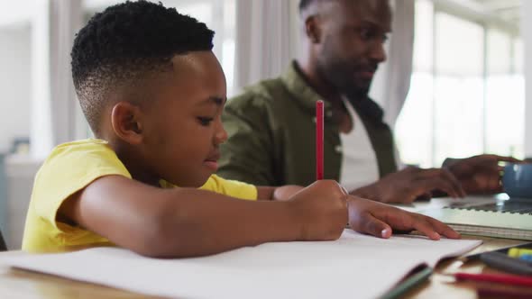 African american father and son doing homework and using a laptop together