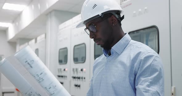 Portrait of an Engineer in a Hard Hat at the Production Blueprint in Hands