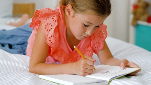 Little Girl Drawing in Sketchbook at Home