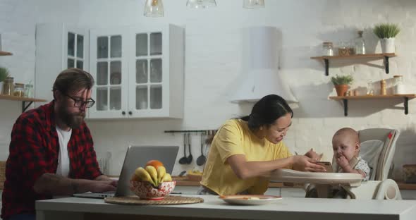 Cheerful Family with Baby Sitting in Kitchen