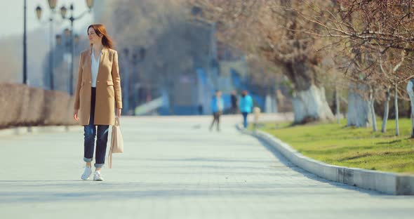 Young Happy Woman Walks on the Square in Early Spring