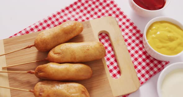 Video of corn dogs with dips on a white surface