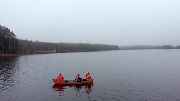 Three Men in Small Orange Boat Fishing on Foggy Autumn Lake in Finland