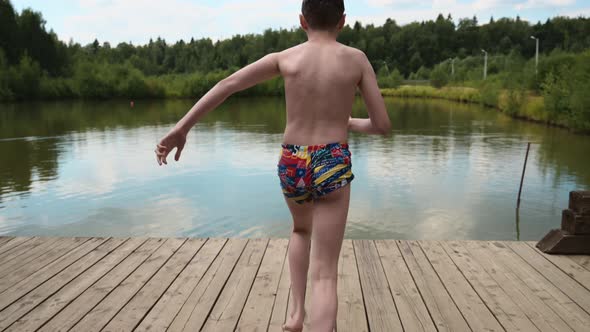 Boy Jumping Into the Lake From the Pier