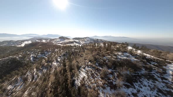 Revealing a snow covered mountains landscape with an FPV drone, descending view