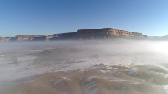 Aerial view of desert cliffs with low fog in the air