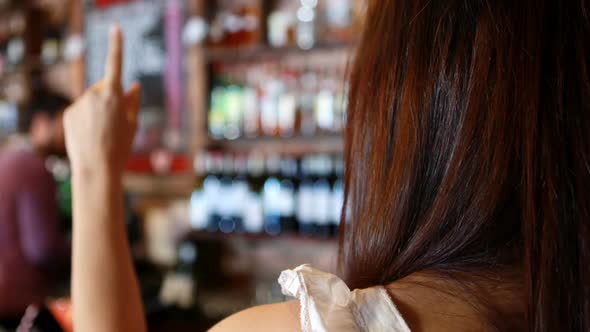 Barman interacting with female costumer at bar counter