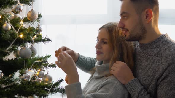 Couple Decorating the Christmas Tree Together in the Christmas Eve