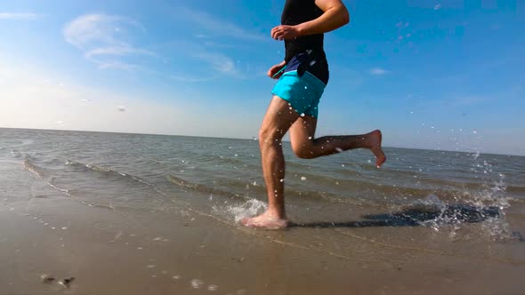 Man in shorts, running in water, on a sunny day, in Germany