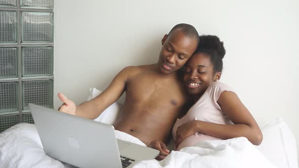 Happy Smiling Couple Watching Film on Laptop at Home
