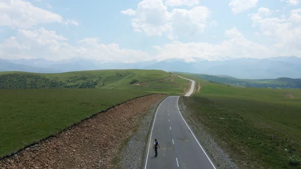 Guy in Summer in Black Clothes Descends From the Mountain on a Skateboard