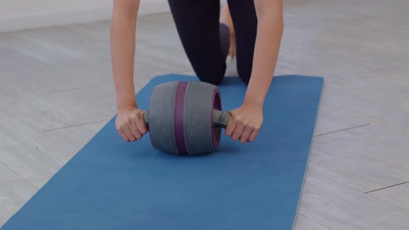 Athlete Asian young woman exercise with ab roller on exercise mat at home