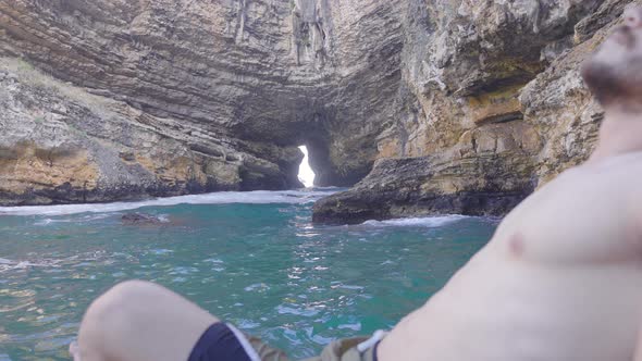 Young man sunbathing in the sea cave.