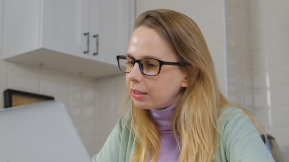 Freelancer woman in glasses talking on laptop computer webcam at home in 4k video