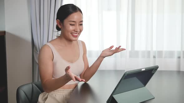 Asian women use tablet for online meetings to chat with girlfriends at home.