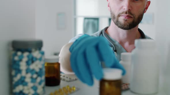 Male Physician Taking Medicines from Shelf while Working in Clinic