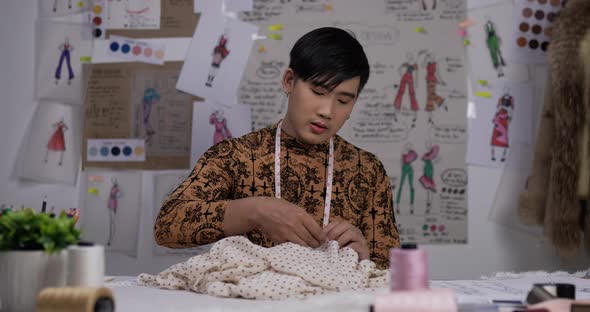 Sleepy fashion designer man sewing in studio