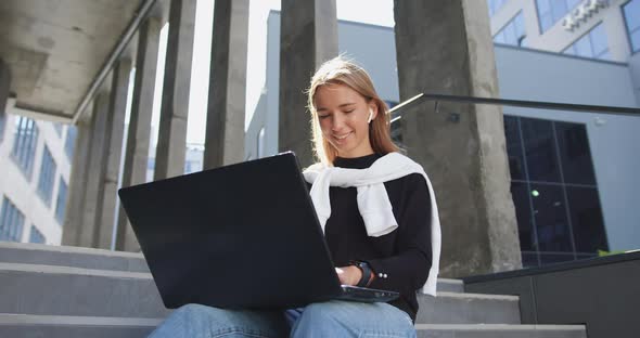 Girl in Casual Clothes which Sitting on Building's Steps, Working on Laptop and Checking Time