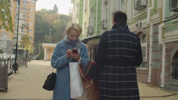 Two Mature Women Obsessed with Phones Running Into Each Other Outdoors