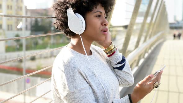 Young black woman listening music singing smartphone