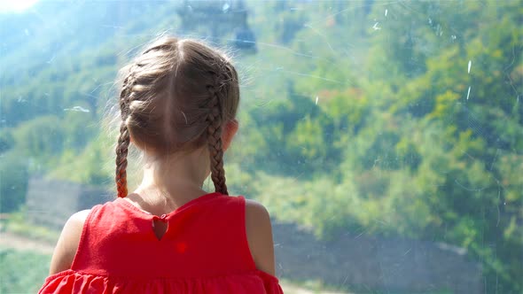 Adorable Happy Little Girl in the Cabin on the Cable Car in Mountains in the Background of Beautful