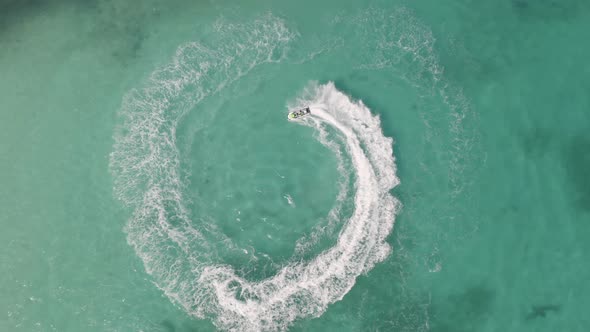 Aerial top view of jet ski or boat drawing a shape on sea ocean turquoise water. Adventure