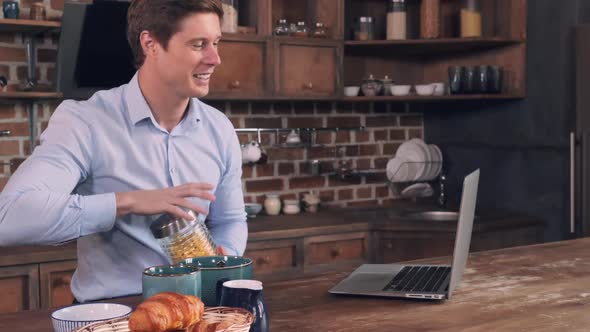 Male Pours Wheat Flakes and Speaking Use Internet.