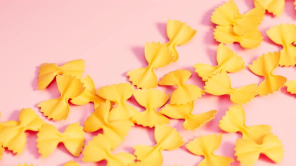 Farfalle bow pasta arranged on pink surface. Seamlessly looping animation.