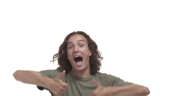 Excited Hipster Guy in Casual Tshirt with Wavy Long Hairstyle Jumping From Bottom and Showing