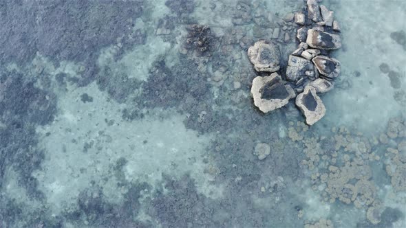 Aerial view of rock cliff and clear water with corals