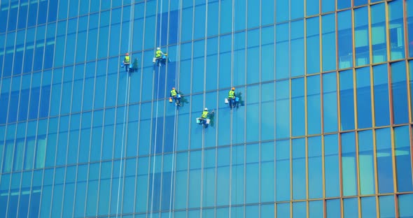 Five Men Workers in Red and Yellow Work Clothes Cleaning the Exterior Windows of a Business
