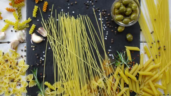 Bunch of Spaghetti Being Dropped on Table with Pasta and Seasonings on It