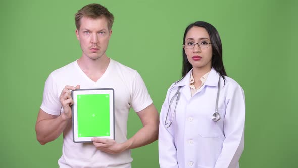 Young Asian Woman Doctor with Young Man Patient Showing Digital Tablet