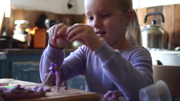 Close up footage of a young five year old girl playing with clay in the kitchen of the house she liv