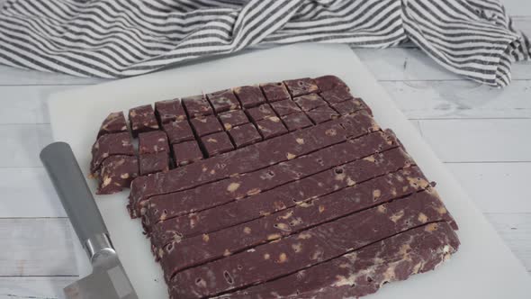 Time lapse. Step by step. Cutting homemade macadamia fudge on a white cutting board