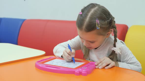 Children's Playroom. Cute Little Girl Paints on a Magnetic Blackboard Special Pen