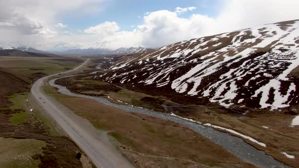 Aerial of highway in prairie with snowy summits of mountain in the background