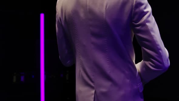 Saxophone Player in a White Suit Performing Against the Backdrop of Neon Lamps in a Dark Studio