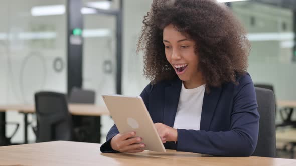 Excited African Businesswoman Celebrating Success on Tablet 