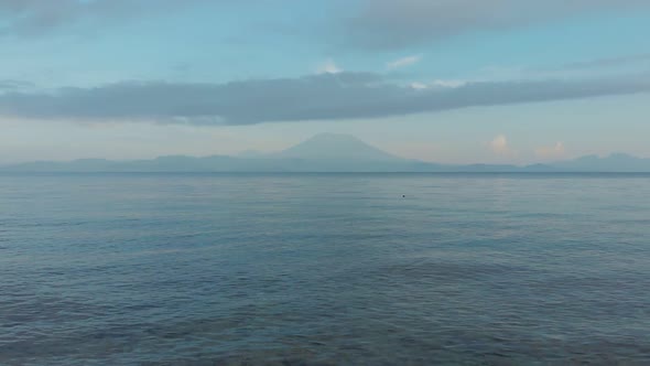 Drone Footage Flying Low Over the Waves of the Sea Against the Backdrop of the Volcano Agung. Bali