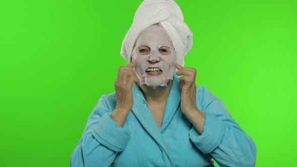 Elderly Grandmother After Shower. Old Woman Applying Cosmetic Fabric Face Mask