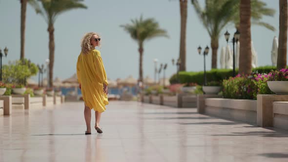 Adult Pretty Woman is Walking on Territory of Luxury Hotel in Summertime