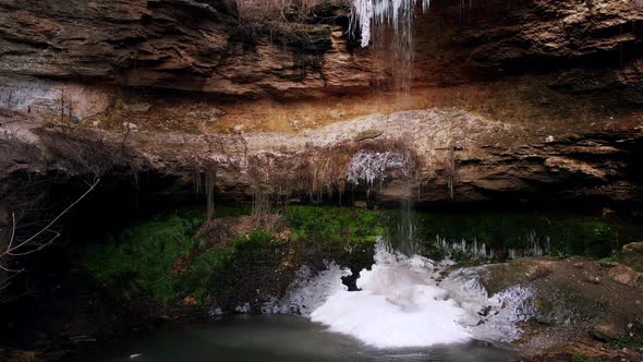 Small Waterfall with Portions of Ice on Wet Rocks and Greenery