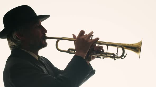 Jazzman in Hat and Suit Plays Music on Trumpet in Studio on White Background Side View