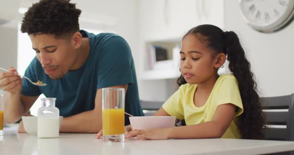 Happy biracial father and daughter eating breakfast together