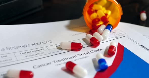 Red and blue cancer treatment drug pills on a prop medical health insurance form showing high patien