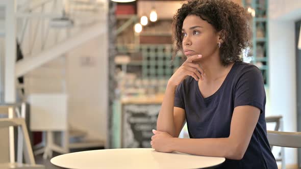 Pensive Young African Woman Thinking in Cafe