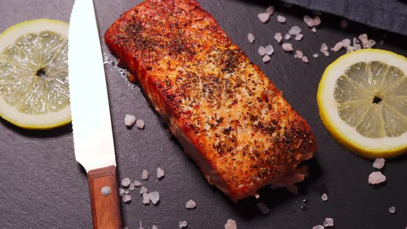 Delicious Baked Golden Salmon on a Black Plate in the Kitchen